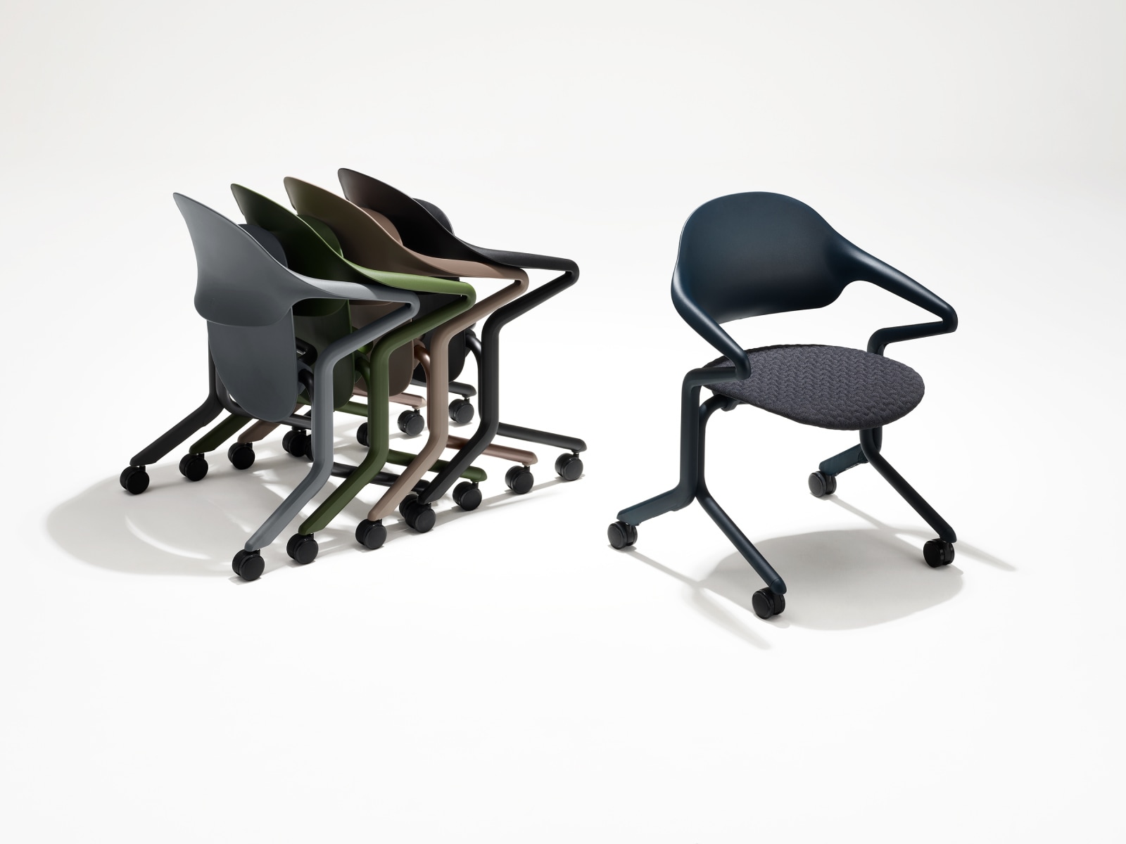 Quattro sedie impilabili Fuld in vari colori e finiture raggruppate accanto a un'unica sedia impilabile Fuld in Nightfall con tessuto a maglia 3D.