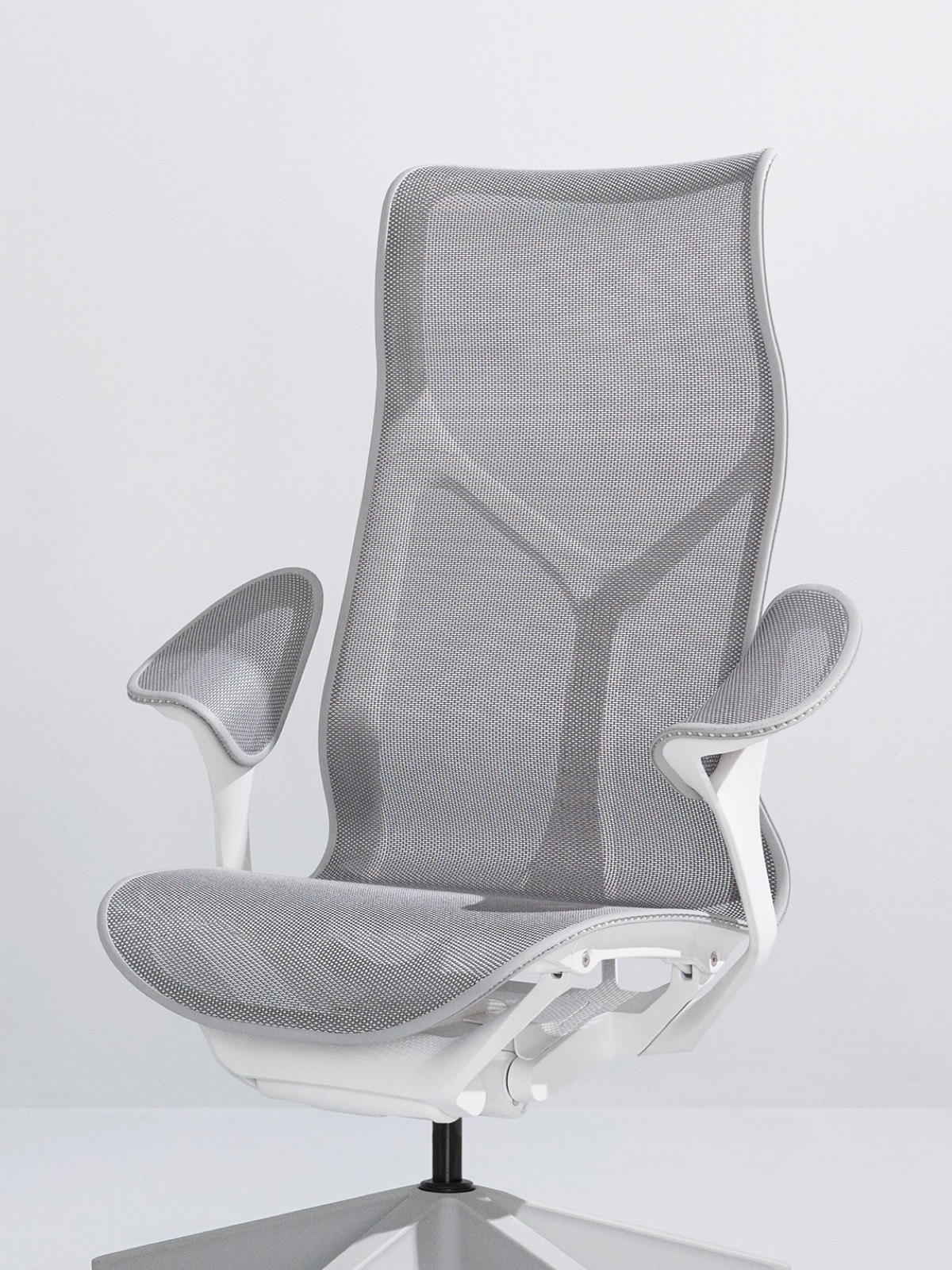 Una sedia Cosm grigia con schienale alto Mineral con montatura bianca e bracci a foglia su fondo grigio chiaro.